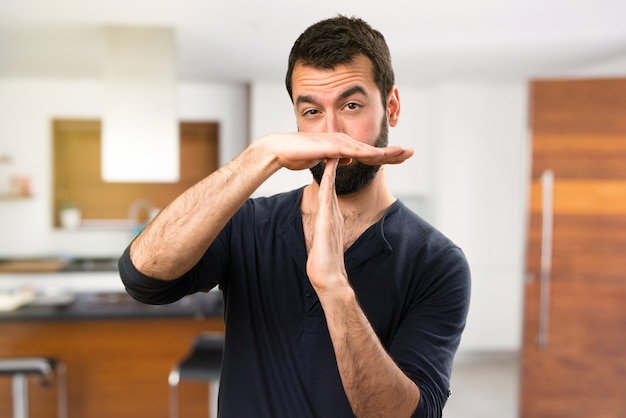 Handsome man with beard making time out gesture inside house