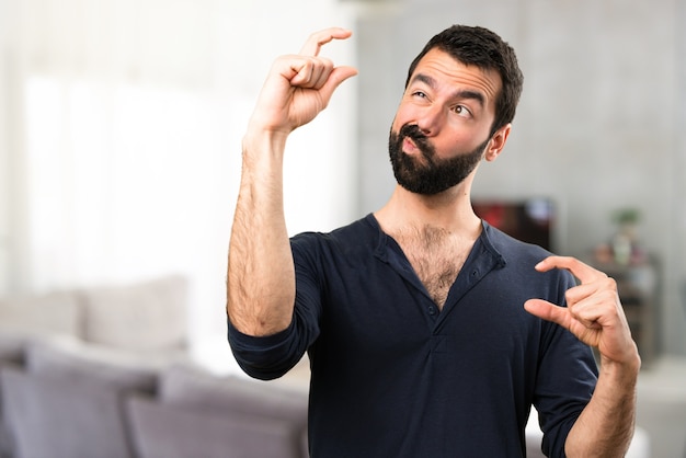 Handsome man with beard making tiny sign inside house