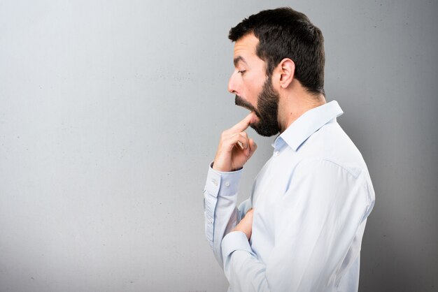 Handsome man with beard making vomiting gesture on textured background