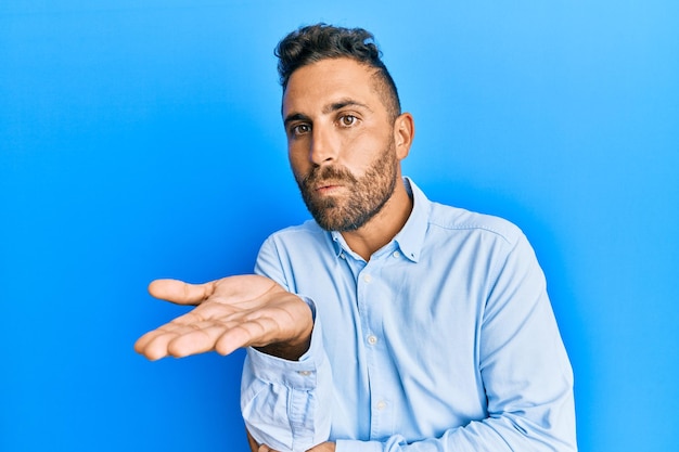 Handsome man with beard wearing casual clothes looking at the camera blowing a kiss with hand on air being lovely and sexy love expression