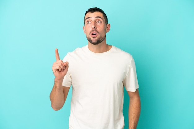 Handsome man with beard over white brick wall keeps palm together. Person asks for something