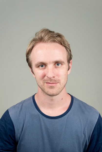  handsome man with blond hair against white wall