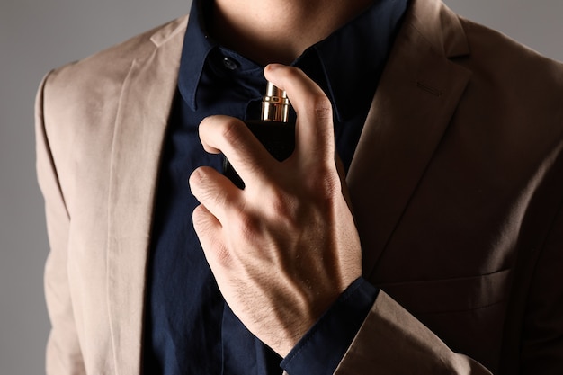 Handsome man with bottle of perfume, closeup