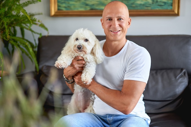 Handsome man with cute white dog at sofa