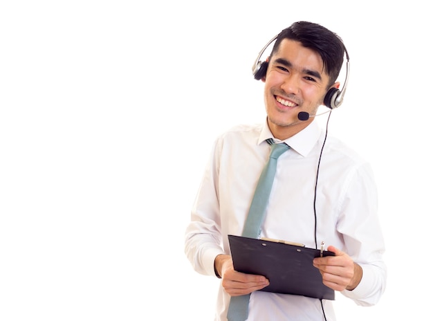 Handsome man with dark hair in white shirt with blue tie using headphones and holding a folder