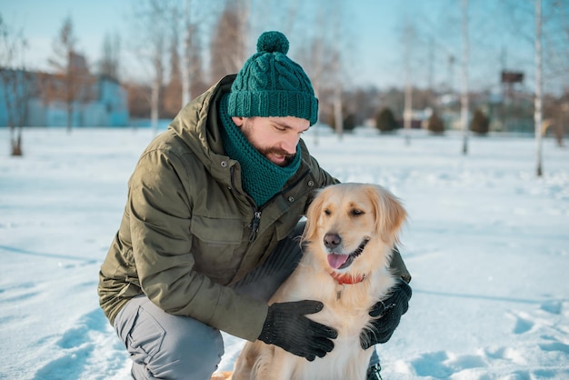 Handsome man with a dog golden retriever walk in spring meadow