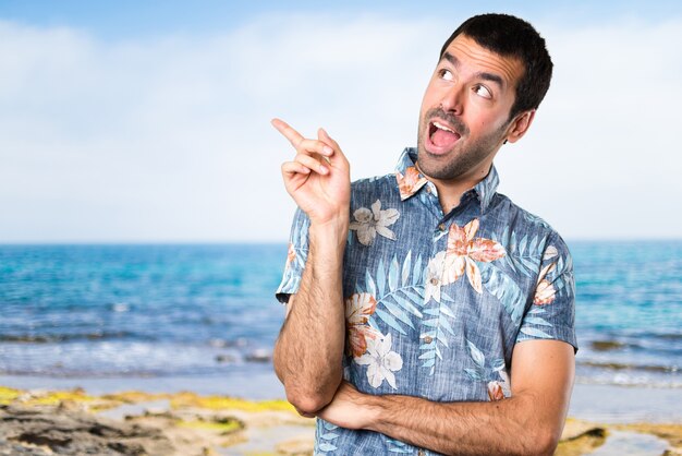 Handsome man with flower shirt thinking at the beach