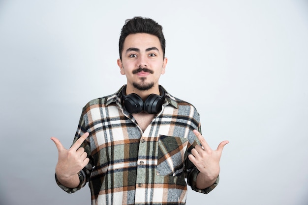 handsome man with headphones posing over white wall.