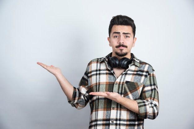 handsome man with headphones posing over white wall.