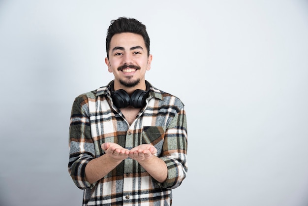 handsome man with headphones standing over white wall.