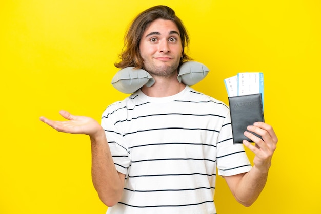 Handsome Man with Inflatable Travel Pillow having doubts while raising hands