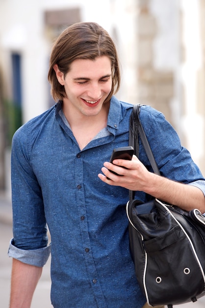 Handsome man with long hair holding smart phone and bag