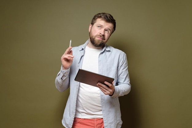 Handsome man with a tablet and a stylus pen is pondering an idea he is thoughtful and unsure