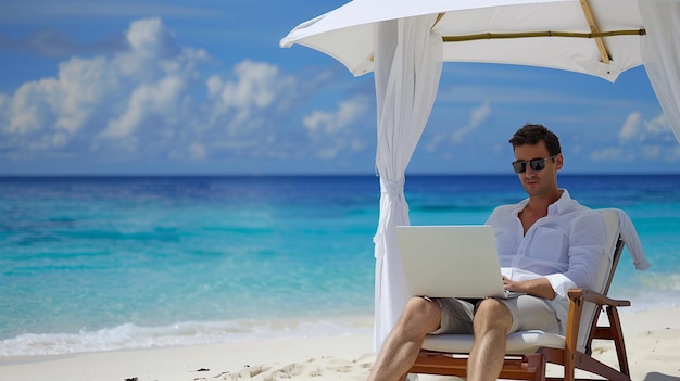 Handsome man working on laptop on beach near blue ocean