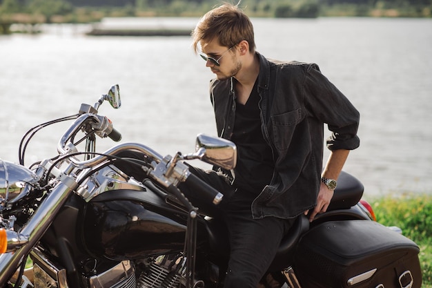 Handsome man or young biker sitting and chilling on the bike chopper outdoors