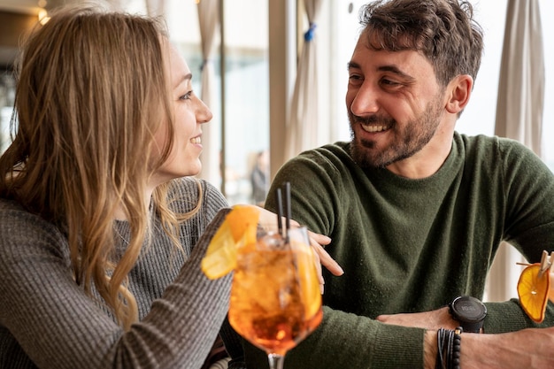 Handsome man and young woman smiling on happy hour at cocktail bar Young lovers couple at beginning of love story Boyfriend and girlfriend hanging out together enjoying after work fancy drinks