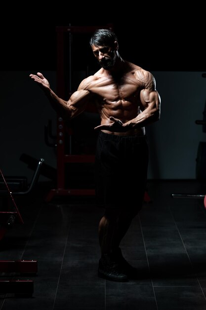 Handsome Mature Man Standing Strong In The Gym And Flexing Muscles - Muscular Athletic Bodybuilder Fitness Model Posing After Exercises