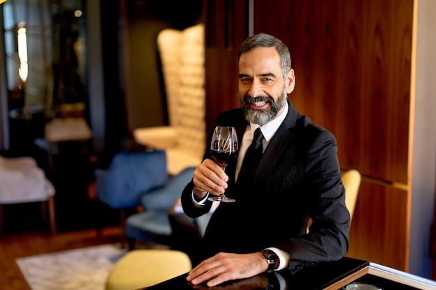 Handsome mature man tasting glass of red wine