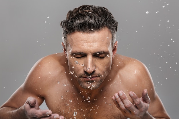 Handsome mature man washing his face.