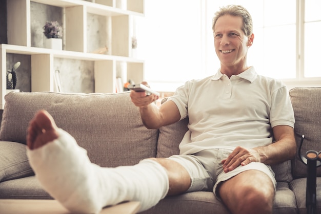 Handsome mature man with broken leg in gypsum.