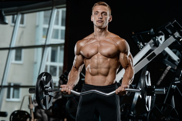 Handsome model young man training arms in gym