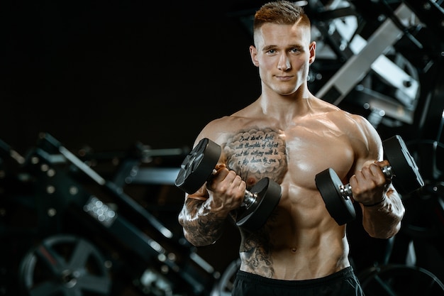 Handsome model young man training arms in gym