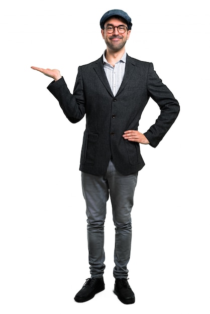 Handsome modern man with beret and glasses holding something imaginary on the palm