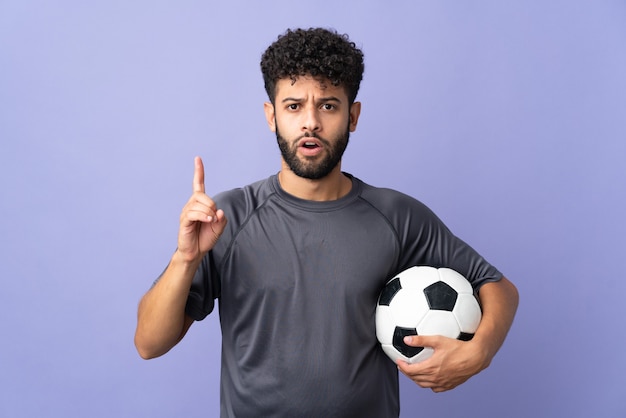 Handsome Moroccan young football player man over isolated on purple wall intending to realizes the solution while lifting a finger up