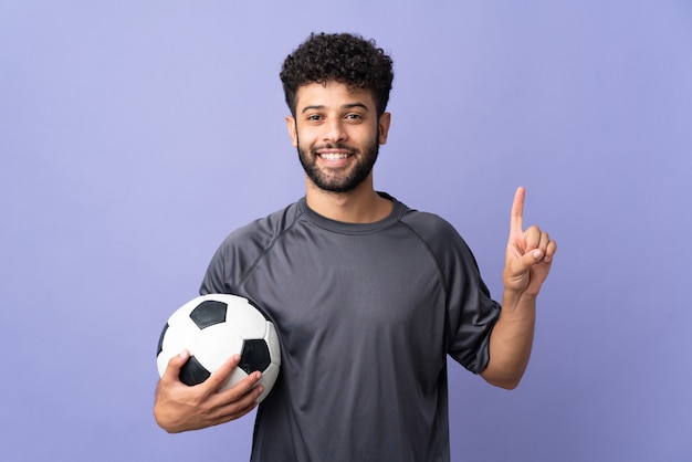 Handsome Moroccan young football player man over isolated on purple wall pointing up a great idea