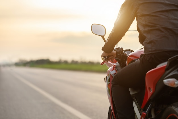 Handsome motorcyclist wear leather jacket sitting on motorbike at the road