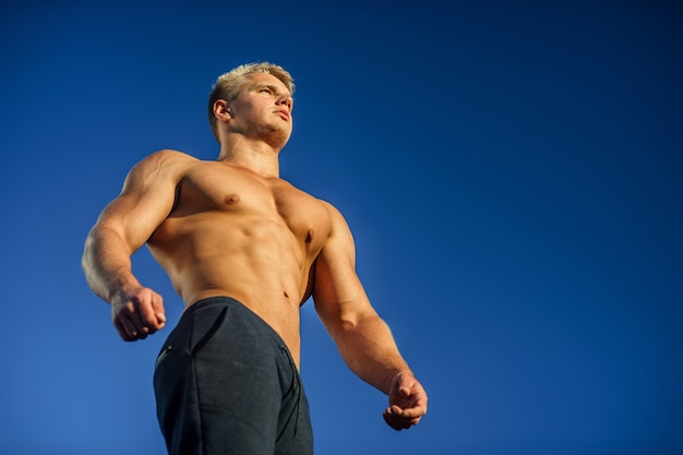 Handsome muscular man posing with blue sky