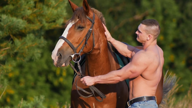 Handsome muscular man riding horse in nature