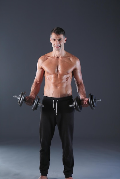 Handsome muscular man working out with dumbbells Personal fitness instructor Personal training