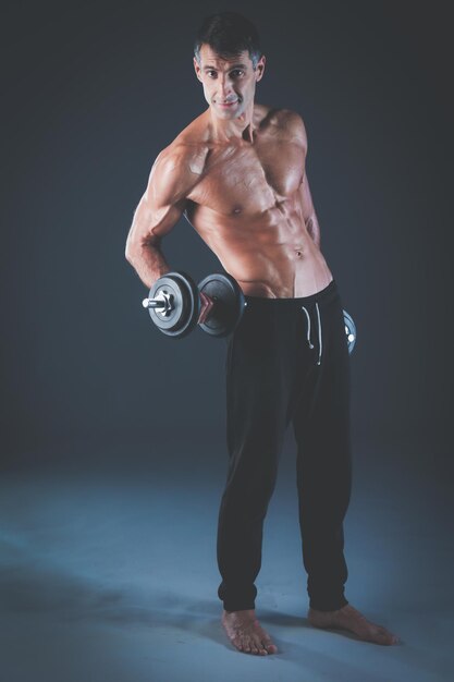 Handsome muscular man working out with dumbbells Personal fitness instructor Personal training