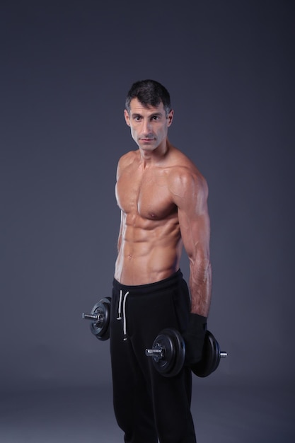 Handsome muscular man working out with dumbbells Personal fitness instructor Personal training