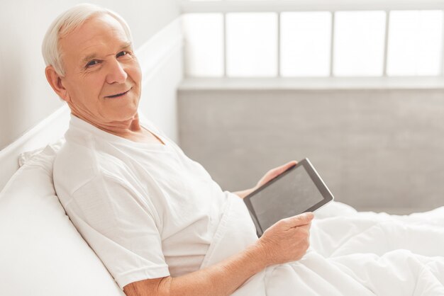 Handsome old man is using a digital tablet.