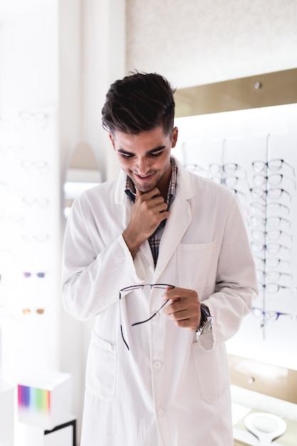 Handsome ophthalmologist choosing eyeglasses frame for his client in optical store.