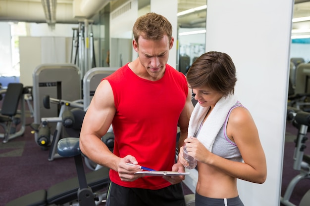 Handsome personal trainer with his client looking at clipboard