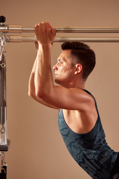 Handsome pilates male instructor performing stretching balance fitness exercise on small barrel