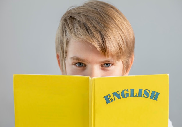 Handsome preteen schoolboy holding yellow english book modern education foreign languages