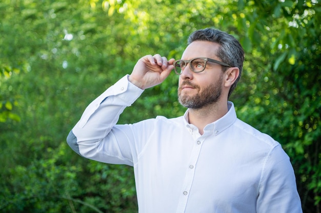 Handsome professional guy in eyeglasses looking up natural background eyesight