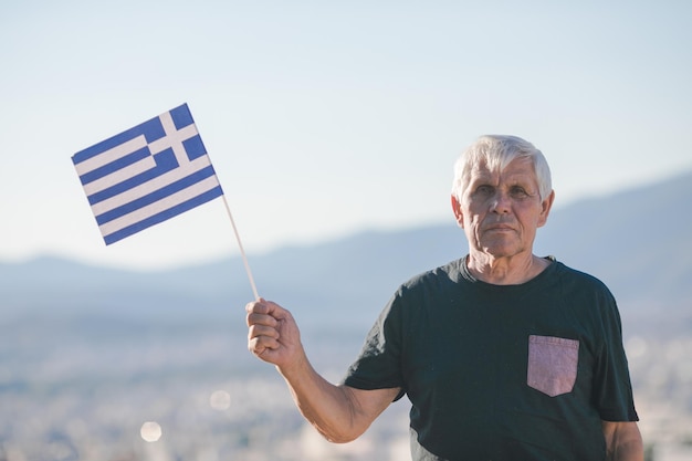 Handsome retired man with grey hair holding greece flag national symbol of Greece