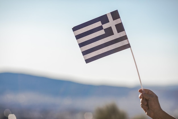 Handsome retired man with grey hair holding greece flag national symbol of Greece