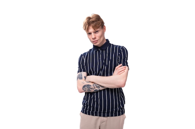 Handsome s blond man dressed in a tank top with tattoos posing on a white background