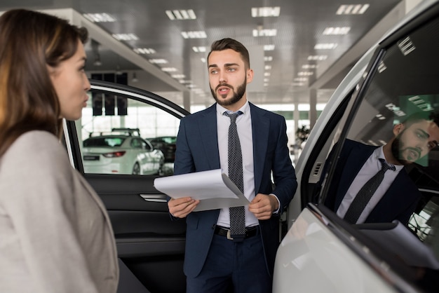 Handsome Salesman Selling Cars in Showroom