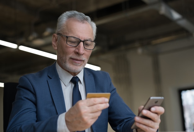 Handsome senior businessman holding credit card