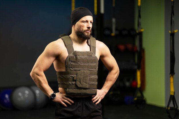 Handsome serious bearded man athlete with bare muscular torso wearing plate carrier training