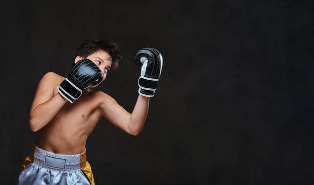 Handsome shirtless young boxer during boxing exercises, focused on process with serious concentrated facial.