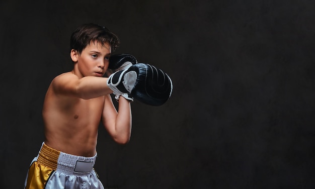 Handsome shirtless young boxer during boxing exercises, focused on process with serious concentrated facial.