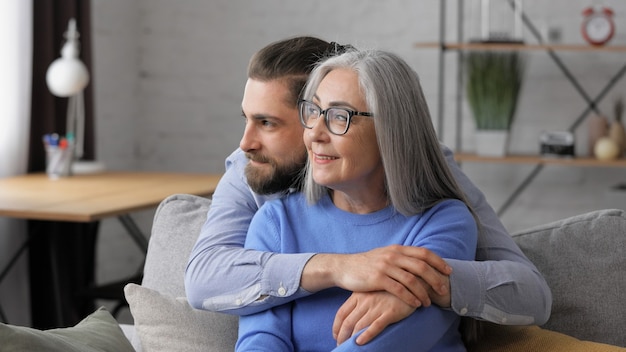 Handsome smiling adult man hugging beautiful senior mature mother.